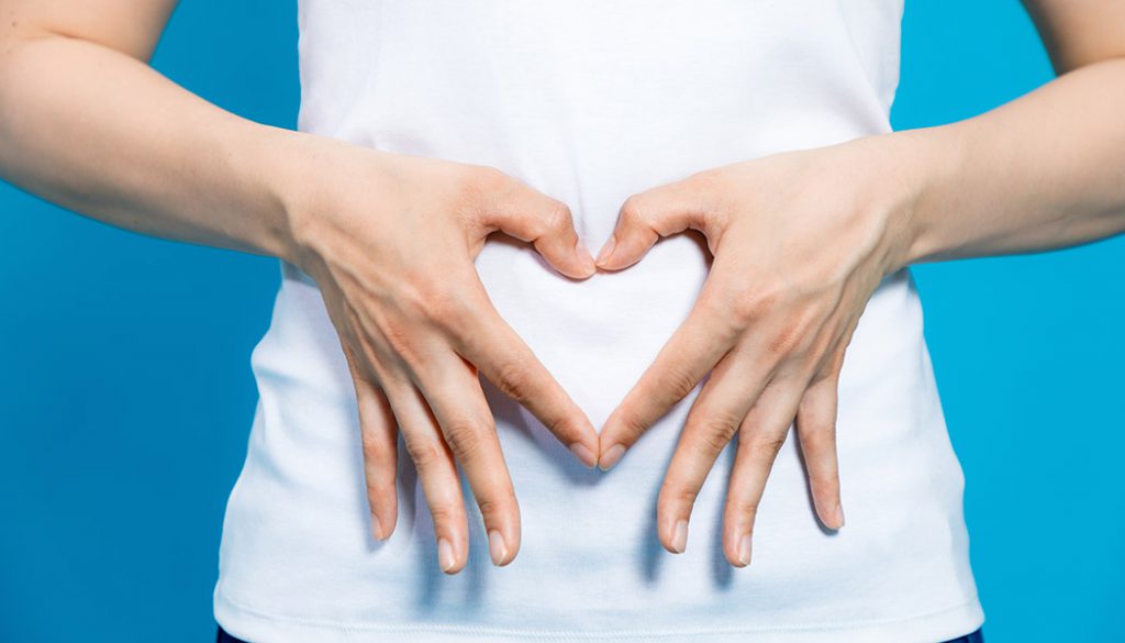 Women makes a heart shape with her hands over her stomach